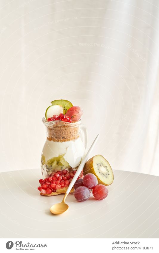 Delicious yogurt dessert with pomegranate, kiwi, grape and ginger biscuit white natural organic diet fruit sweet healthy food breakfast fresh red snack closeup