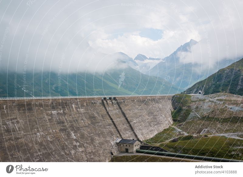 Huge dam with road in mountain region impressive high alpine breathtaking mist cloudy barrier grand embankment artificial magnificent majestic spectacular