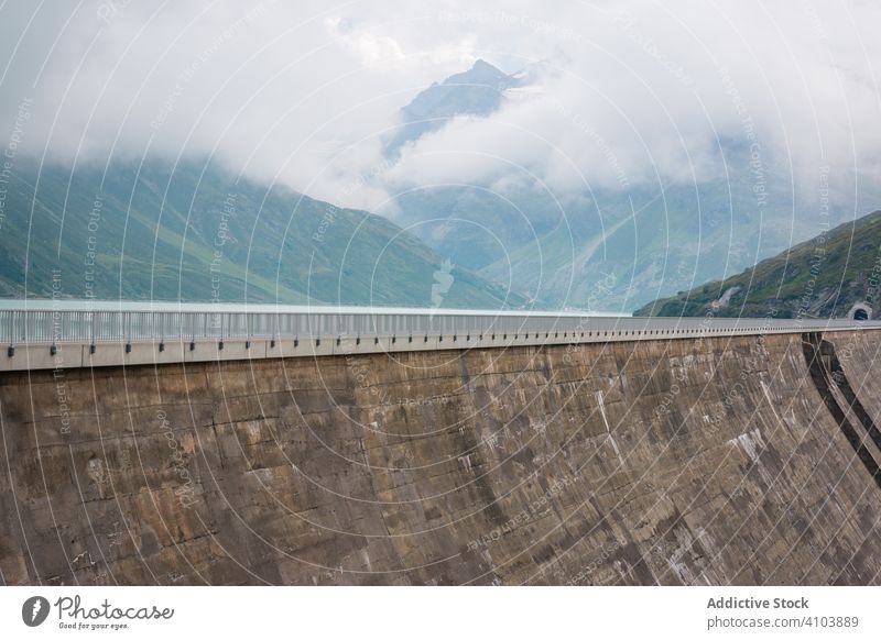Huge dam with road in mountain region impressive high alpine breathtaking mist cloudy barrier grand embankment artificial magnificent majestic spectacular