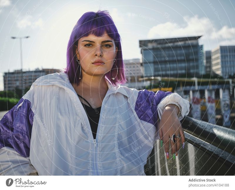 Woman with purple hair leaning on metal fence woman stylish urban hairstyle jacket shiny district confident fashion young model street human female exterior