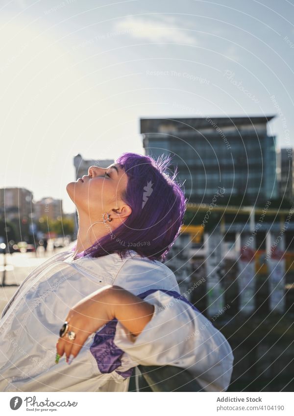 Woman with purple hair leaning on metal fence woman stylish urban hairstyle jacket shiny district confident fashion young model street human female exterior