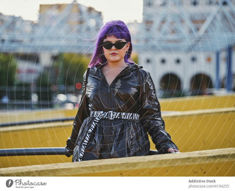Woman with purple hair near metal construction woman stylish urban hairstyle jacket sunglasses shiny fence yellow fashion young model street human female outfit