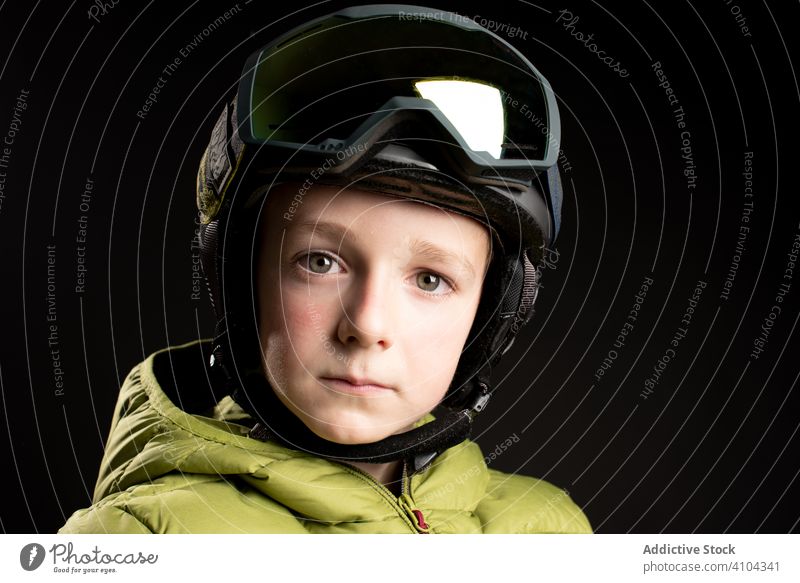 Serious little child in ski equipment in studio kid sportive winter ski goggles skier boy male healthy ready protection warm active vacation sportswear extreme