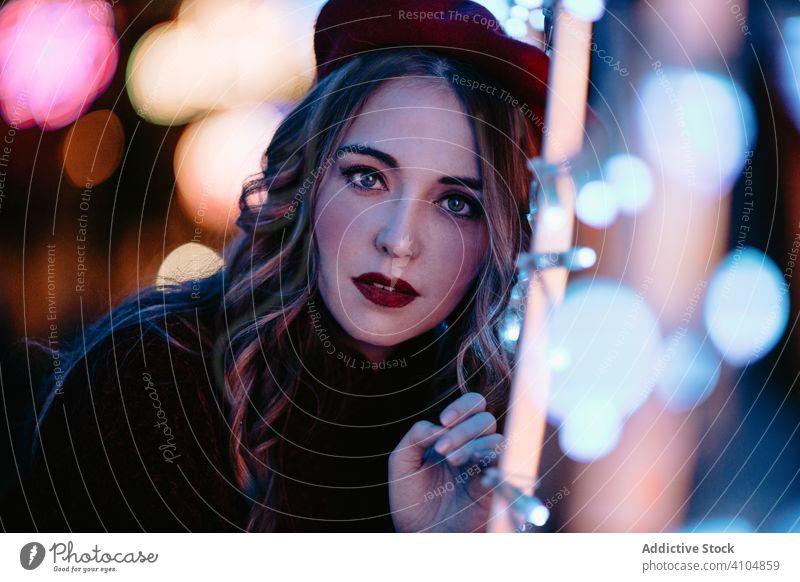 Charming lady in hat enjoying decoration lights at city street woman night christmas amazed wow excited dream casual xmas makeup dark smile laugh touch
