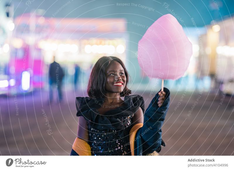 Cheerful African American woman with cotton candy fairground smile entertainment night stylish weekend ethnic female young funfair candy floss sweet treat
