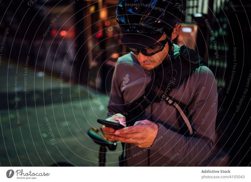 Professional cyclist with smartphone man using browsing bicycle bike city mobile phone street asphalt road equipment eyeglasses male helmet sport lifestyle