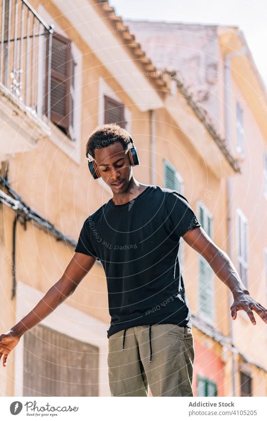 Focused young black man listening to music in street hipster headphone lifestyle student relax entertainment song male youth modern gadget connection audio