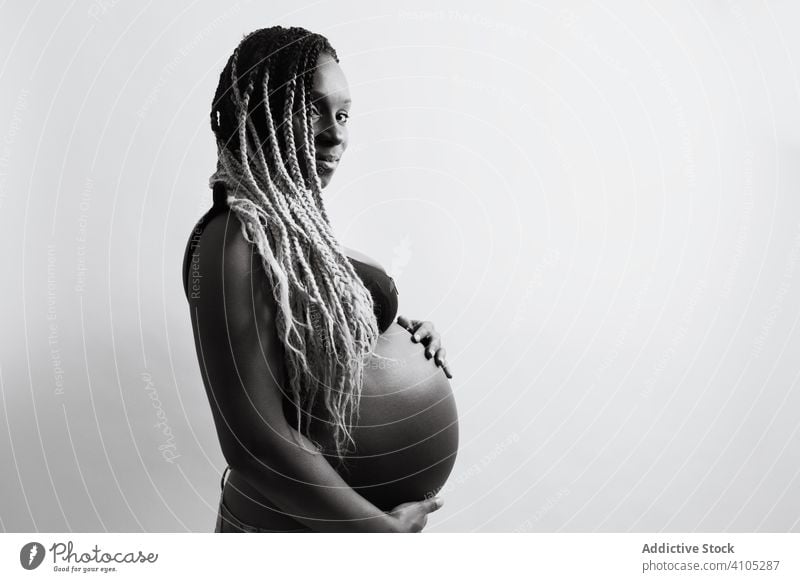 Happy African American pregnant woman holding hands on belly touching happy cheerful expecting maternity motherhood pregnancy baby childbearing anticipation