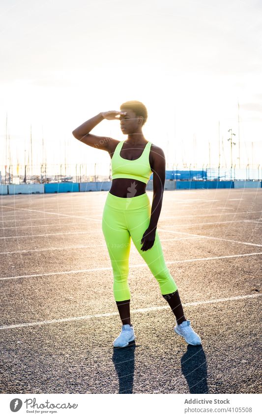Confident ethnic sportswoman before training on sports ground during sunset confident motivation street focus serious physique slim aspiration athletic