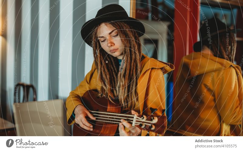 Hipster millennial female playing ukulele guitar woman hipster music stylish room antique vintage hawaiian stand focused concentrated practicing musician