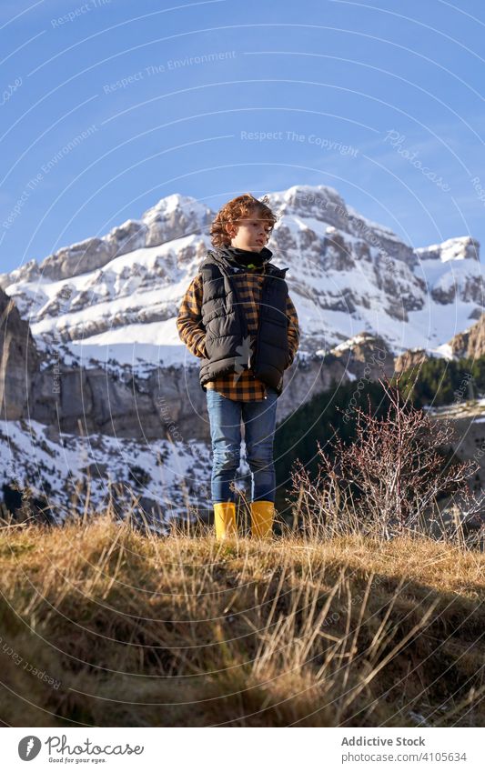 Thoughtful boy standing on dry hill in valley nature journey mountain travel pensive dream adventure hiking observe contemplate active tourism explore vacation