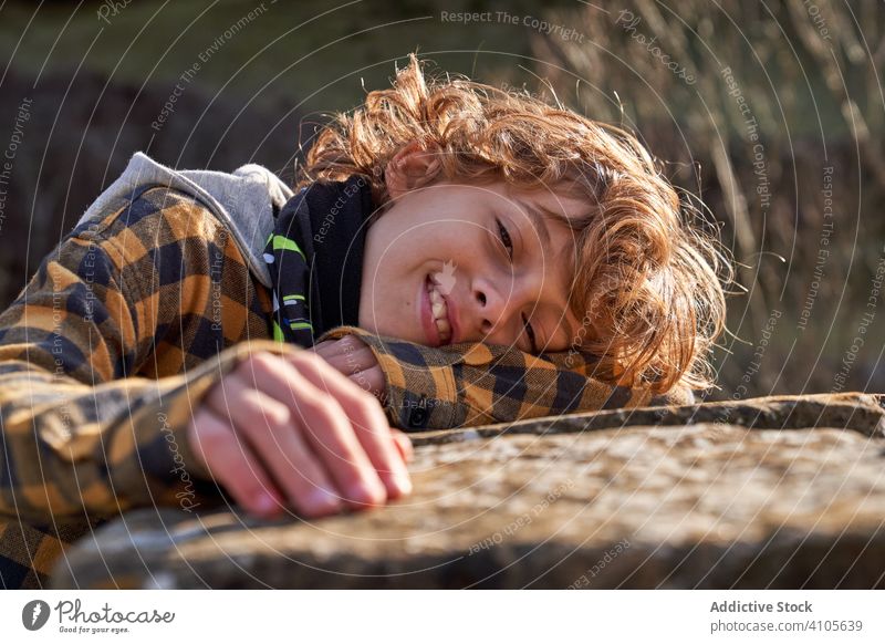 Sad and tired boy leaning on stone broken fence in forest child dream pensive nature cold gentle alone ancient valley childhood little unhappy kid contemplate