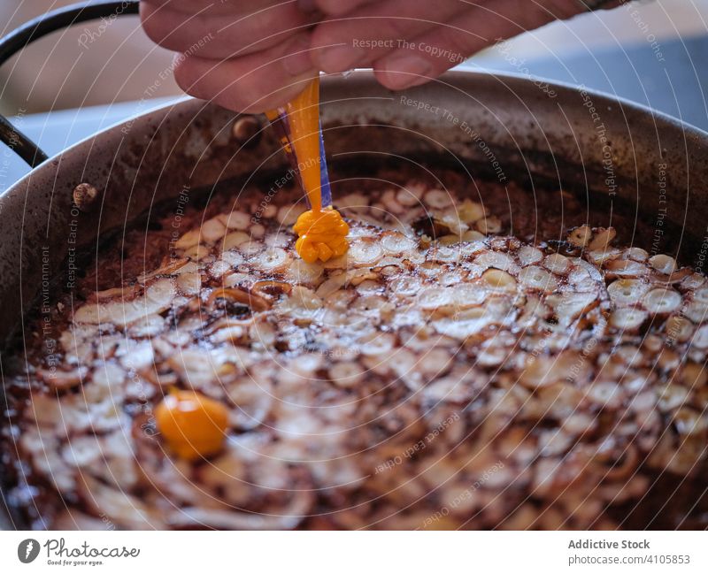Unrecognizable chef serving gastronomic platter with sauce cooking dish haute cuisine using pastry bag pan rice carpaccio octopus orange plate pepper aioli