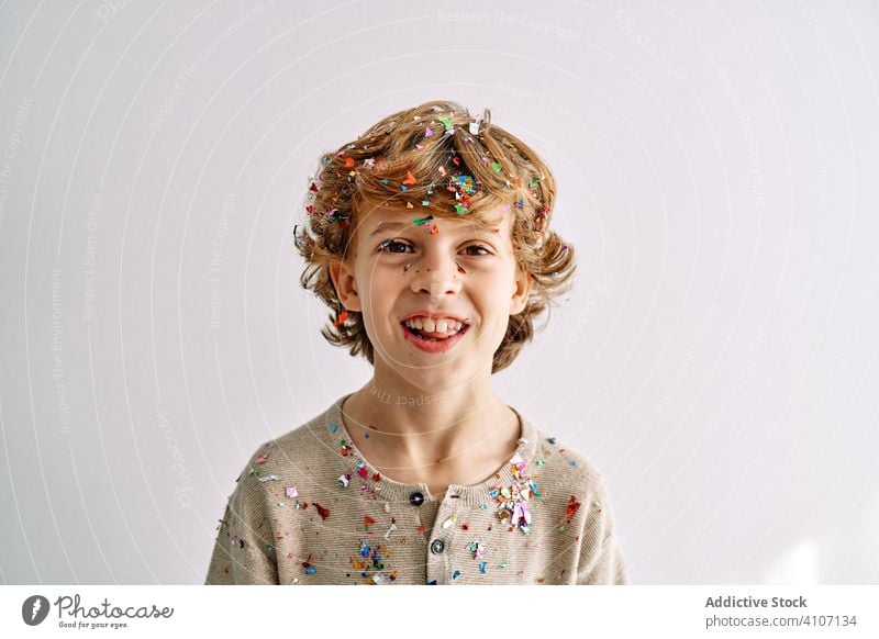 Overjoyed boy having fun with confetti at home play toss throw child male teen colorful smile enjoy laugh modern childhood lifestyle celebrate holiday festive