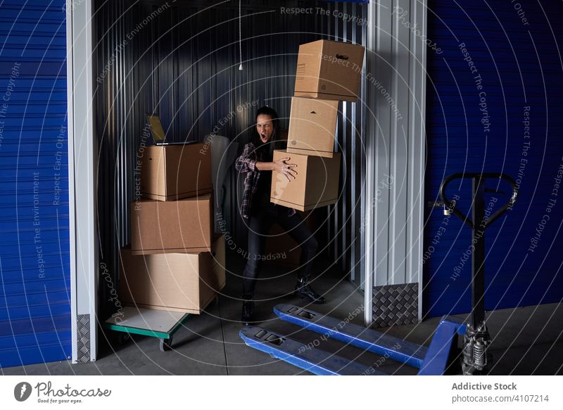 Woman carrying boxes inside a self storage woman relocation day package parcel indoors adult transportation hurry human real delivery profession estate motion