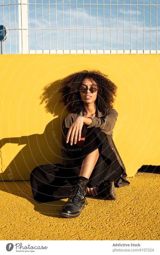 Confident young ethnic woman sitting on ground on stadium confident hipster lifestyle colorful beauty individuality personality female femininity pastime rest