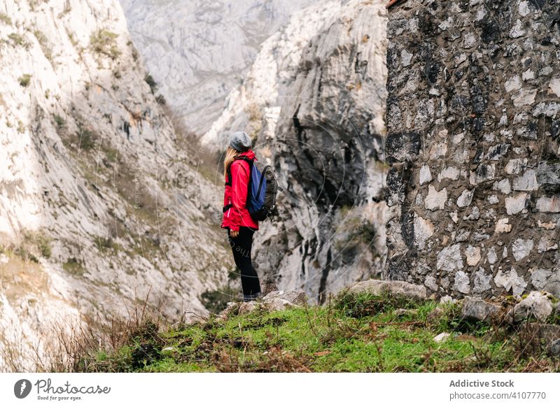 Tourist with backpack standing among high rocks tourist peak mountain hill travel nature dry trekking landscape sky tourism adventure dangerous extreme scenery