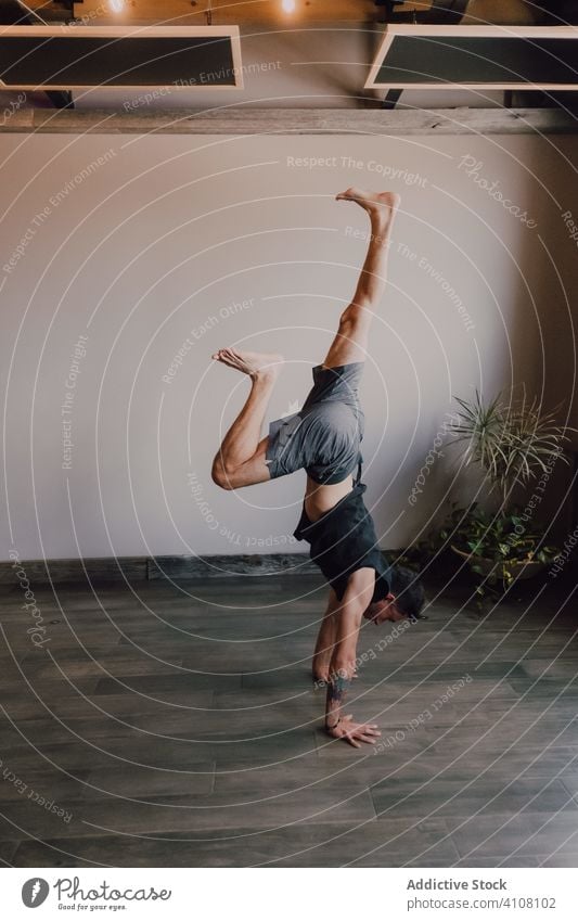 Sportsman practicing yoga in handstand position in modern studio gymnastic athletic practice upside down downward facing dog pose professional training