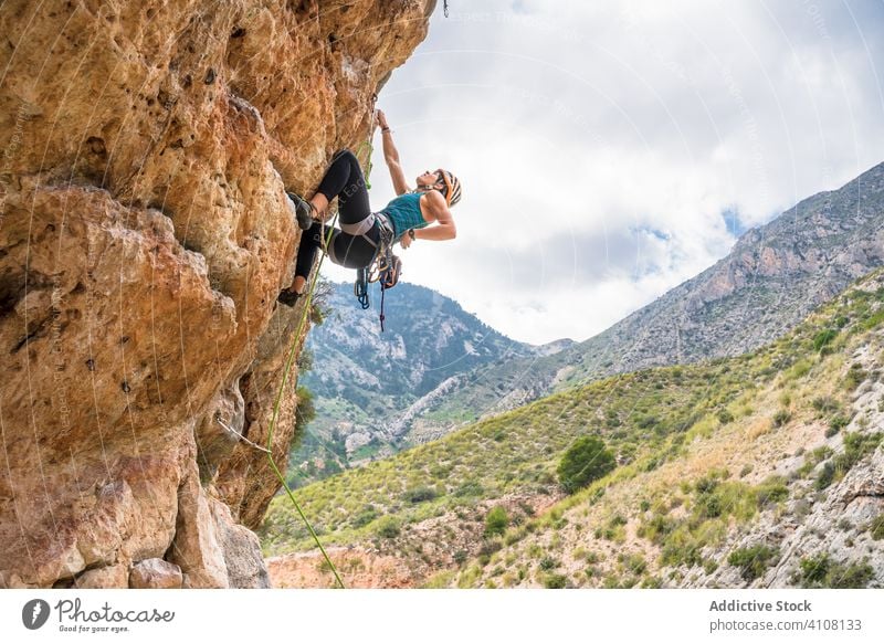 Unrecognizable female climber ascending on sheer cliff in summer woman alpinist mountain practice climbing active mountaineering risk travel extreme freedom