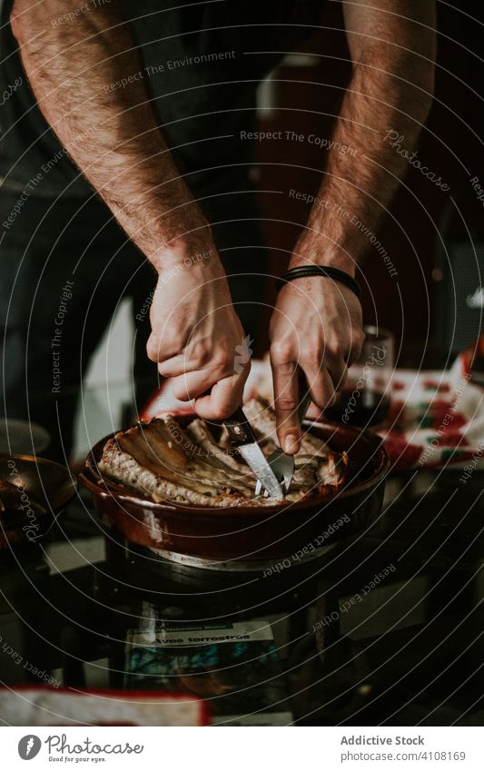 Faceless male cooker preparing roasted ribs with knife in kitchen dish meat cutting fork pan metal served prepare hands man food cuisine rustic rural tool ready