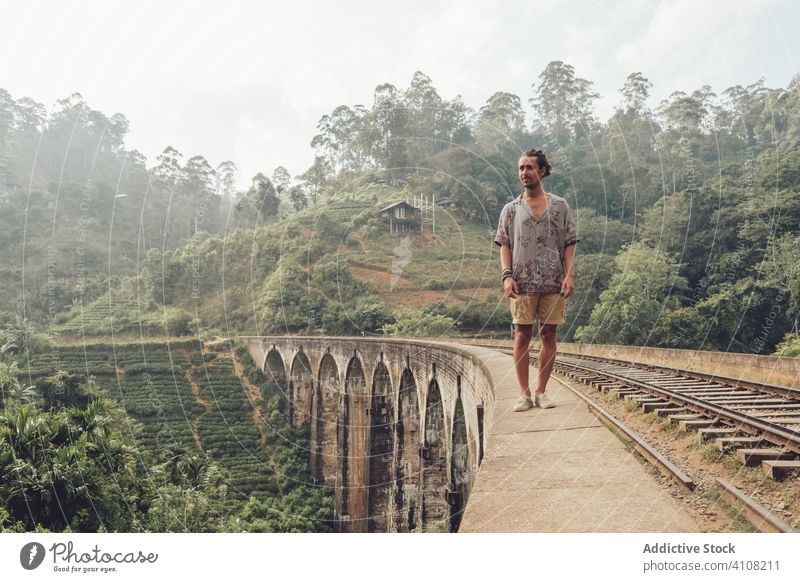 Male tourist walking on fence of bridge in tropical landscape in fog man tourism explore travel railway edge old historic aged ancient male countryside nature