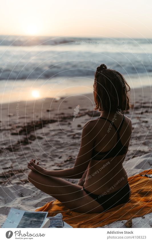 Unrecognizable woman meditating on beach in sunset meditate practice yoga lotus pose spirit asana posture serene lifestyle relax seashore dusk female sandy