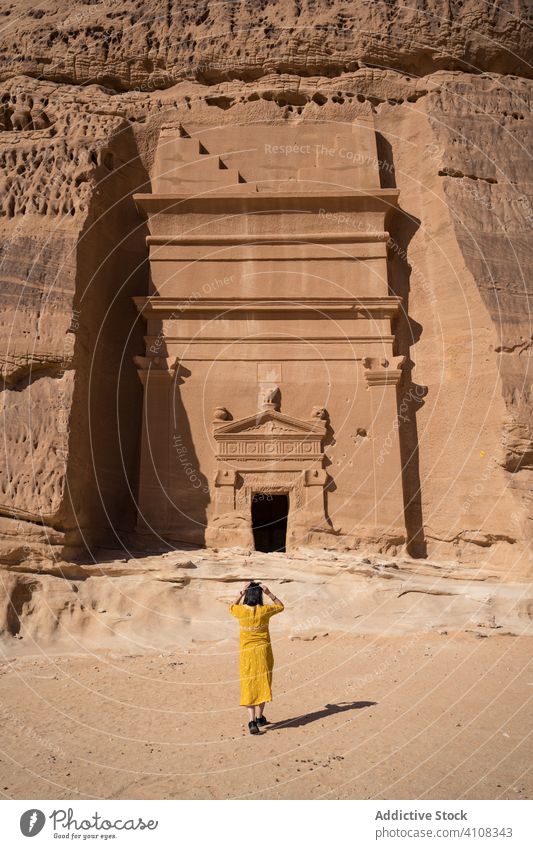 Anonymous female tourist enjoying sightseeing in desert woman tomb carved cliff traveler freedom vacation tourism culture grave religion architecture old