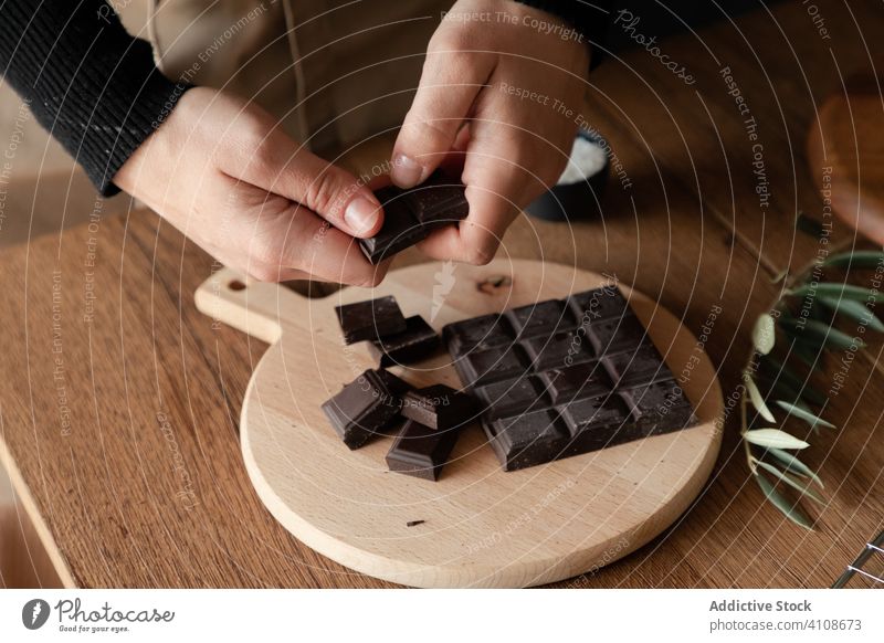 Woman breaking chocolate bar in kitchen food prepare cook woman recipe ingredient table wooden sweet dessert female hand process piece home pastry handmade