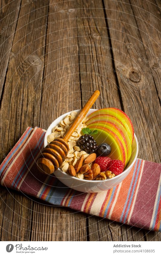 Bowl with nuts fruit and berries with honey dipper super food breakfast healthy nutrition berry fresh apple cereal diet organic meal blueberry bowl almond table