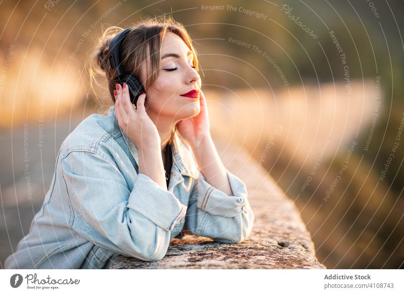 Woman enjoying music with headphones woman listen smile closed eyes casual female nature style delight lifestyle rest modern sound song audio young lady relax