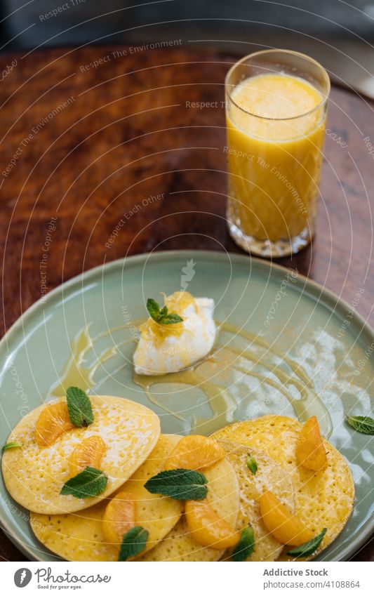 Tasty breakfast of pancakes and juice in restaurant haute cuisine slice piece tangerine sauce topping mint glass colorful sweet cream portion orange morning