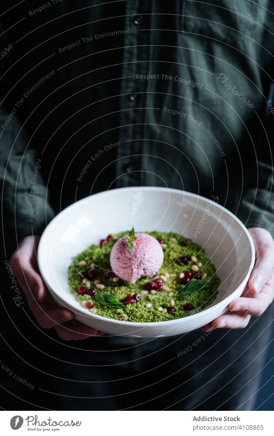 Anonymous person holding bowl with dessert ice cream nuts mousse haute cuisine restaurant scoop green delicious food yummy tasty dish ball sorbet plate flavor