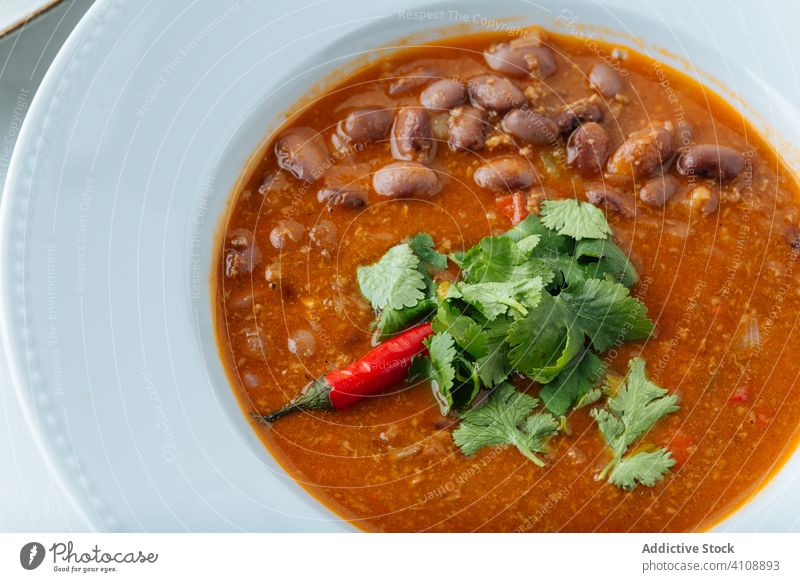 Spicy soup with beans in restaurant herb pepper parsley red hot food tradition lunch chili meal delicious fresh healthy tasty dish nutrition bowl culinary mix