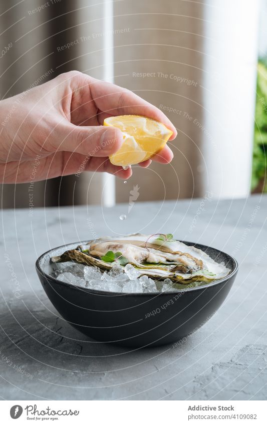 Crop person squeezing lemon on oysters eat squeeze restaurant ice table clam seafood exquisite delicious tasty yummy palatable delectable savory dish meal