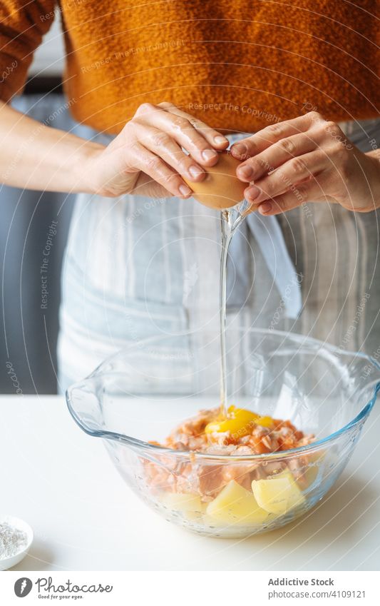 Woman adding egg into bowl with food ingredients break cooking mix stuffing woman recipe fish salmon potato kitchen glass transparent healthy meal female