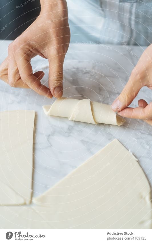 Cook twisting dough into croissant on table cook bagel flour rolling pin preparation sliced bakery homemade culinary making kitchen dessert recipe food raw