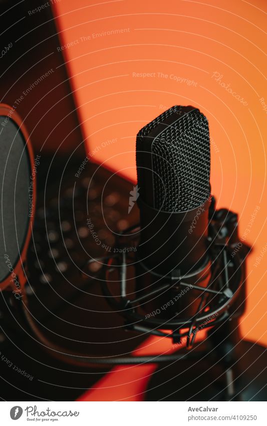 Close up mock up of a streaming microphone with a laptop over an orange background with copy space, minimal concept, technology streaming mockup pink blue