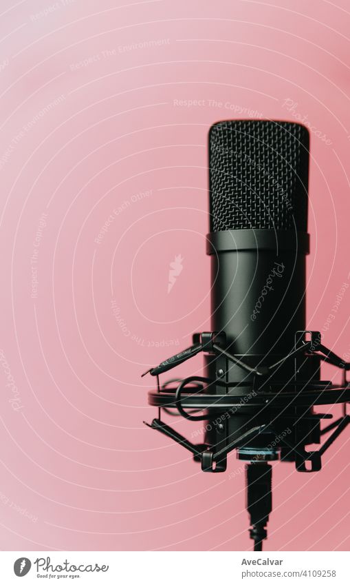 Minimalistic image of a streaming microphone over an pastel pink background with copy space, minimal concept, technology streaming mockup blue streamers