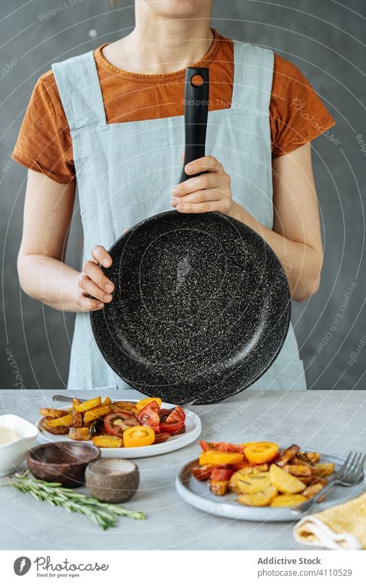 Crop woman with frying pan after food preparation cook kitchen dish fried vegetable plate female home meal ingredient roasted baked casual tasty delicious yummy