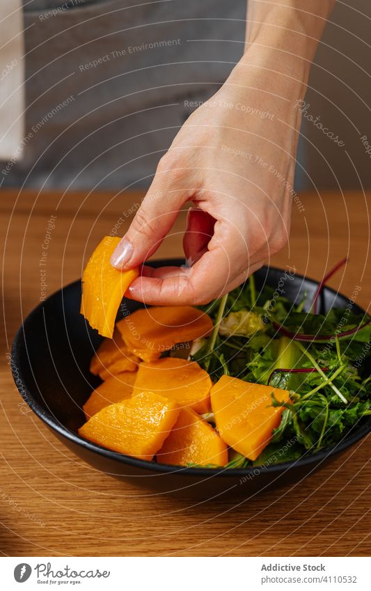 Crop person taking piece of pumpkin from bowl cook dish vegan herb kitchen food preparation home meal ingredient culinary diet cuisine organic natural recipe