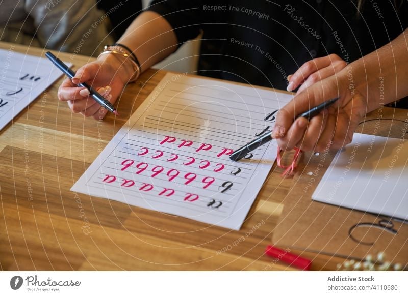 Faceless woman learning lettering at table draw paper handwriting occupation desk workplace art creative craft graphic education notebook skill stationery