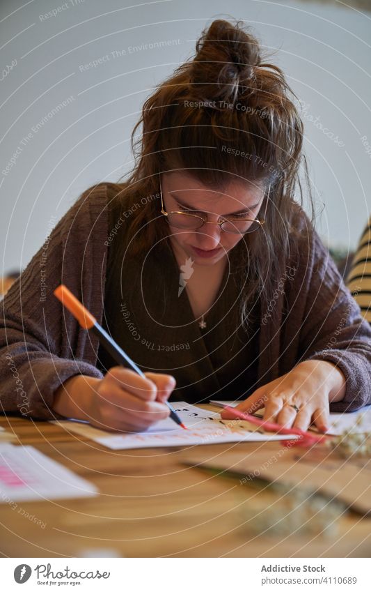 Female artist drawing with pencil in art studio woman lettering handwriting concentrate creative focus lifestyle study job sit sketch inspiration table paper