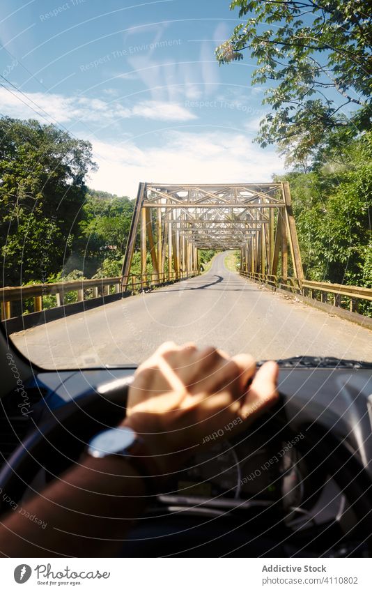 Crop person driving car towards bridge drive road trip transport countryside route journey costa rica steer travel nature vehicle lifestyle ride asphalt summer