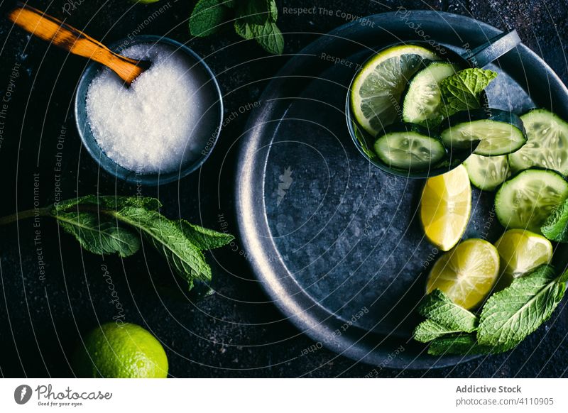 Ingredients for cucumber detox drink on table ingredient lime mint sugar lemon cup tray dark fresh healthy natural citrus fruit spoon mug composition