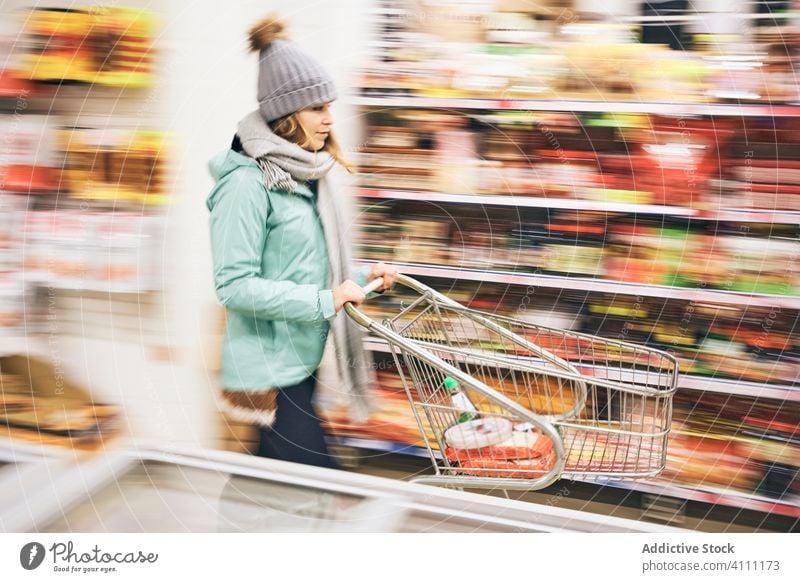 Woman choosing purchases in supermarket woman store cart food shopper customer buy grocery defocused motion retail product trolley choose commerce choice buyer