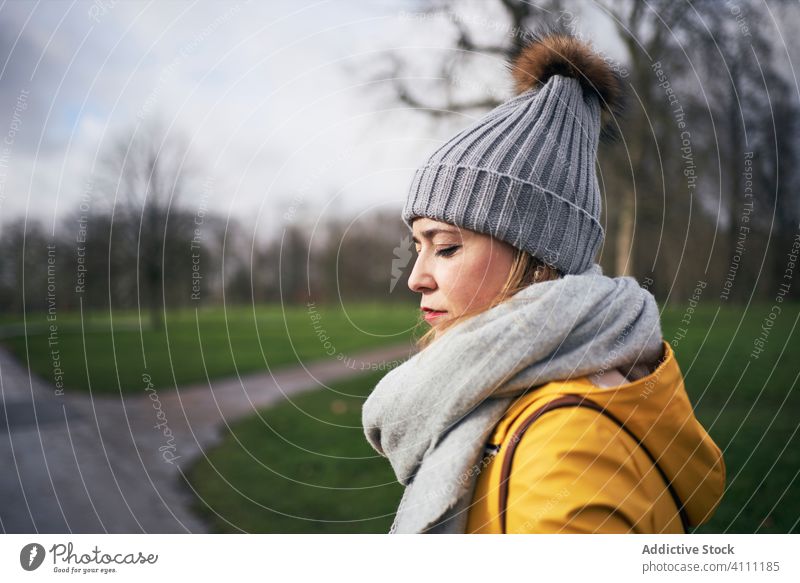 Woman in warm clothes strolling in gloomy park woman tranquil cold alone season serene peaceful style autumn young hat scarf outfit calm relax appearance female