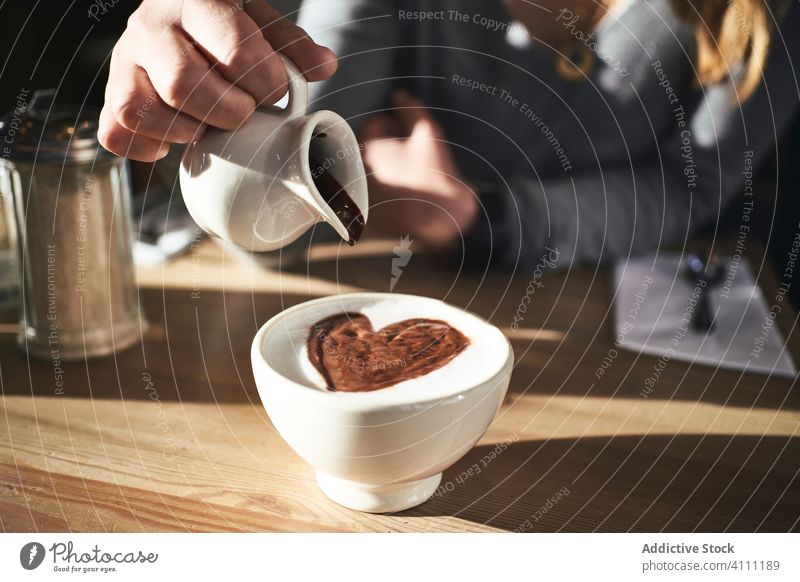 Anonymous woman adding chocolate syrup into hot drink cup beverage cafe warm cold table pour sweet cacao food warm clothes female delicious tasty modern aroma