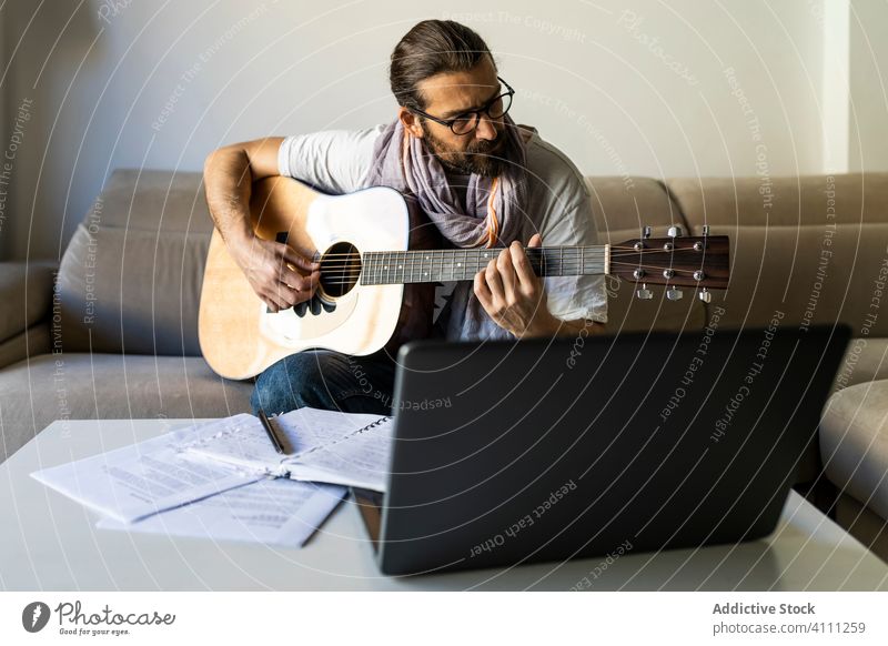 Stylish guitarist on couch in living room man play sit sofa male casual music songwriter composer poet home lifestyle talent instrument melody perform lesson