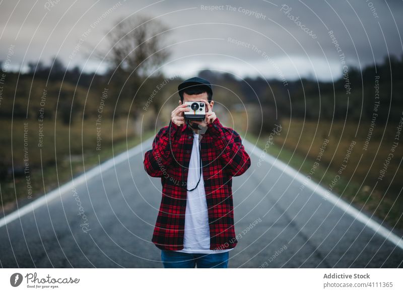 Anonymous man with photo camera in countryside road nature casual male shoot hobby tourism travel trip adventure young equipment journey creative instant camera