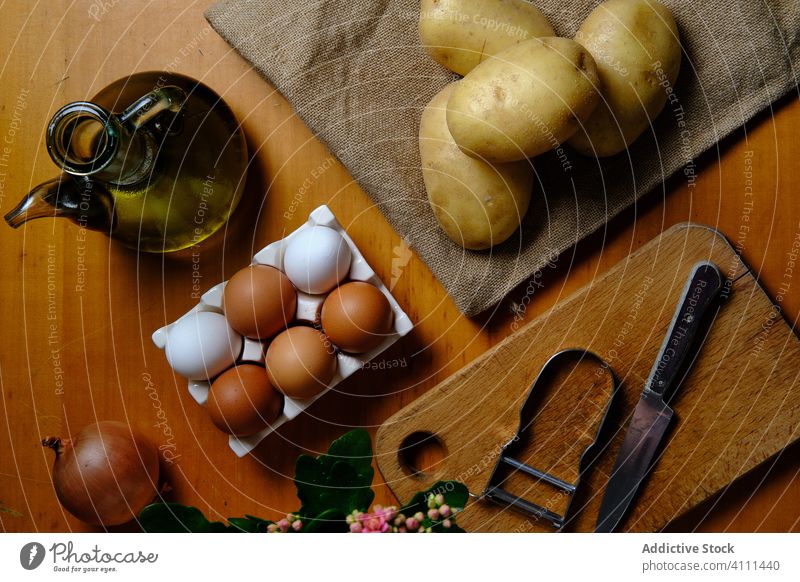 Ingredients and tools for recipe on table potato egg oil ingredient prepare olive onion knife peel kitchen wooden food fresh cook organic cuisine culinary
